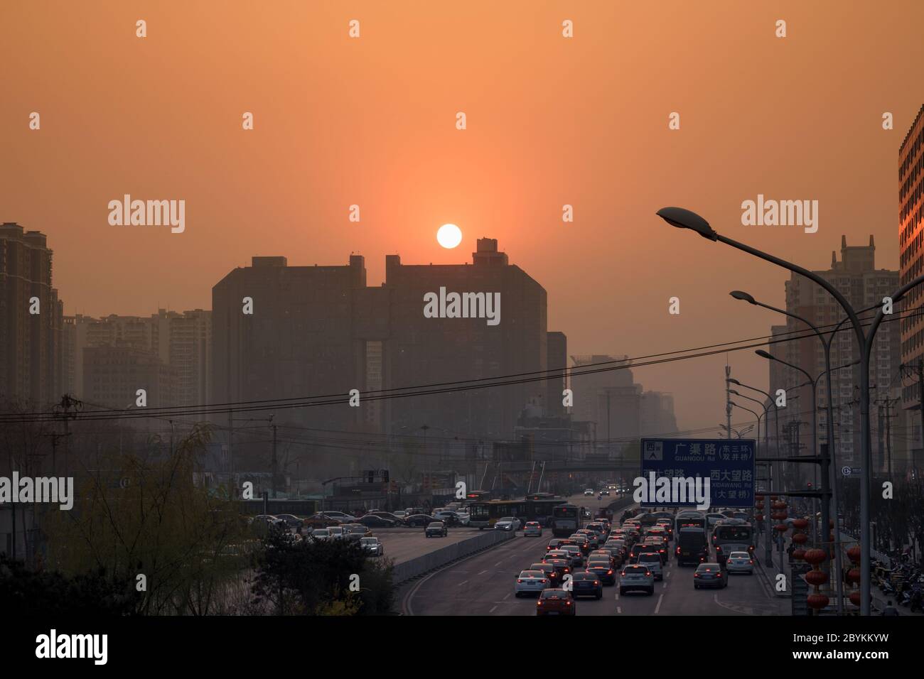 Peking / China - Mai 2019 : Sonnenuntergang während eines sehr verschmutzten Tages über der Dawang Road in der Nähe des Hopson One Shopping Mall Stockfoto