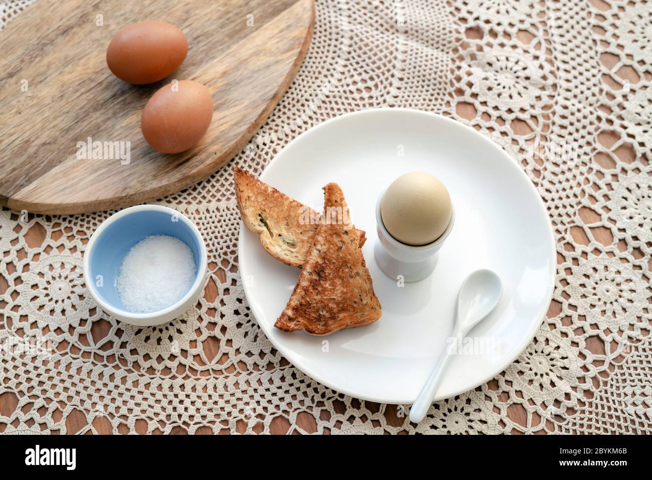 Leckeres gekochtes Ei in einer Tasse mit knusprig geröstetem Brot zum Frühstück. Gesundes Essen auf dem Küchentisch. Stockfoto