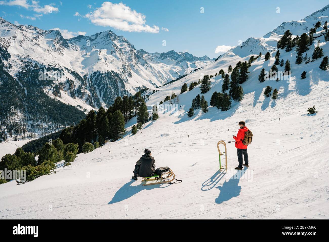 Auf Holzschlitten bergab fahren. Happy Influencer Spaß mit Holz Vintage Rodeln auf schneehohen Bergen - natürliche Schlittenbahnen Stockfoto