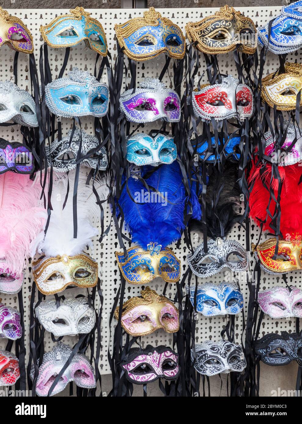 Ausstellung von mehrfarbigen Karneval Augenmasken einige mit Federn auf Verkauf in einem Geschäft in Venedig, Italien Stockfoto