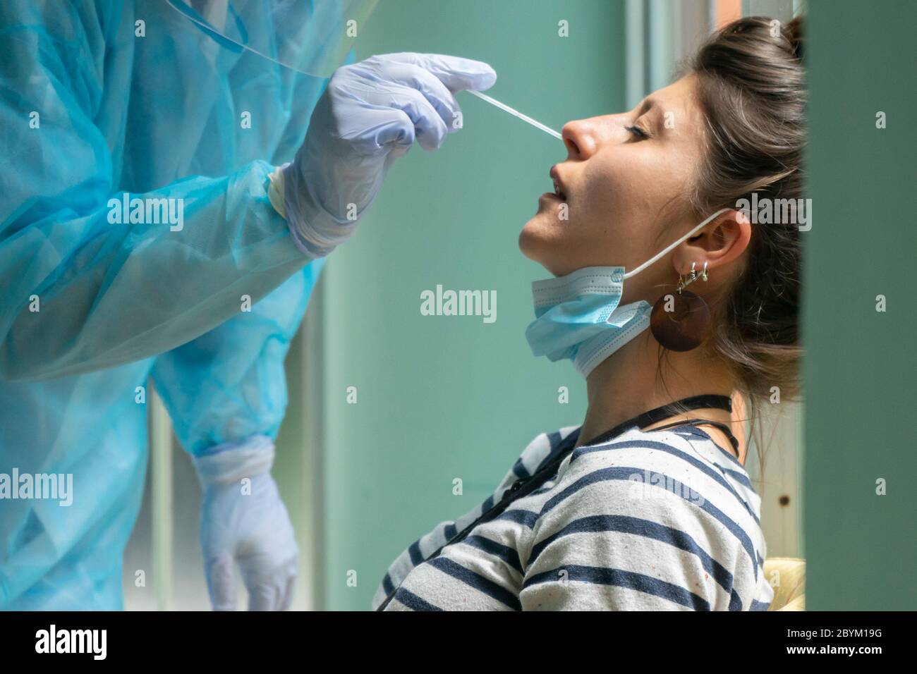 Gesundheitsarbeiter mit Schutzausrüstung führt Coronavirus Abstrichbesteck auf kaukasischen Mädchen.Nasenabstrich für Covid-19. Stockfoto