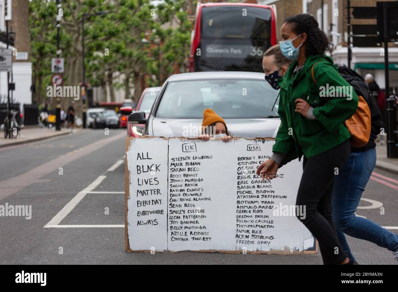 Ein Mädchen, das auf einer Straße sitzt und ein Schild den Verkehr während eines Black Lives Matters Protests blockiert, London, 7. Juni 2020 Stockfoto