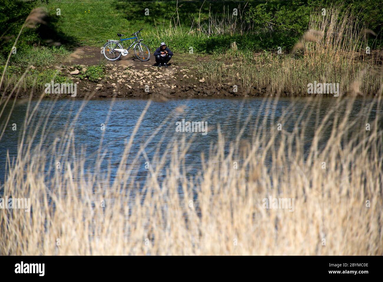 04.05.2020, Bremen, Bremen, Deutschland - Junge Mann mit Fahrrad am Ufer der Lesum, Bremen-Nord. 00A200504D079CAROEX.JPG [MODELLFREIGABE: NEIN Stockfoto