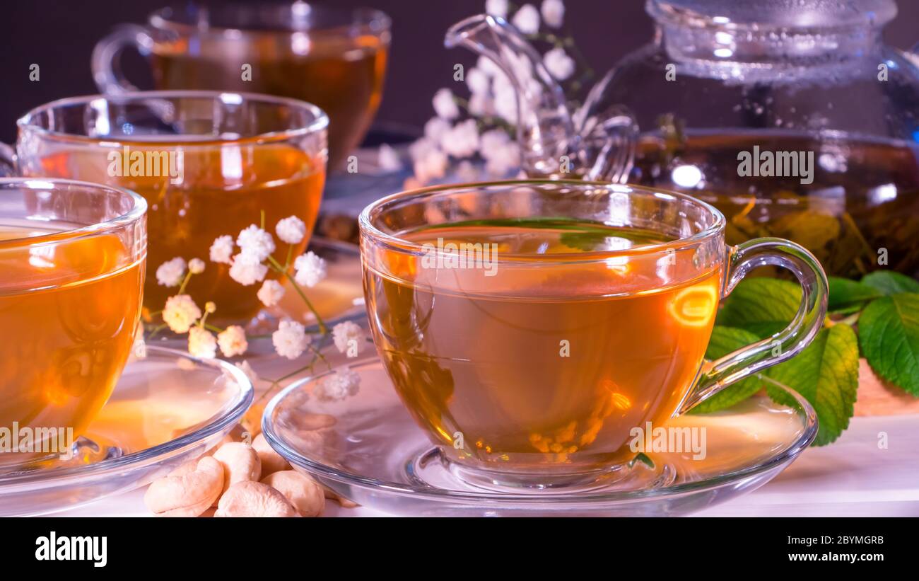Teekanne und Tassen mit grünem Tee, Cashewnüssen, grünen Blättern und weißen Zigeunerblüten.Teezeremonie, traditionelles Getränk. Nachmittagstee, heimelig. Orien Stockfoto