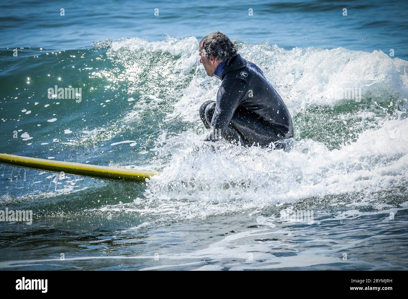 Surfer fängt an, eine Welle zu fangen, die nicht groß genug zu sein scheint, um zu fahren, aber als er beginnt, zu gehen, beginnt es, viel kleiner und langsamer zu werden. Stockfoto