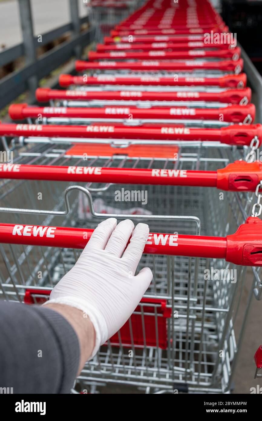 13.04.2020, Berlin, Berlin, Deutschland - Hand mit einem Einweghandschuh am Griff eines Einkaufswagens vor einem Supermarkt. MC200413D935CAROEX.J Stockfoto