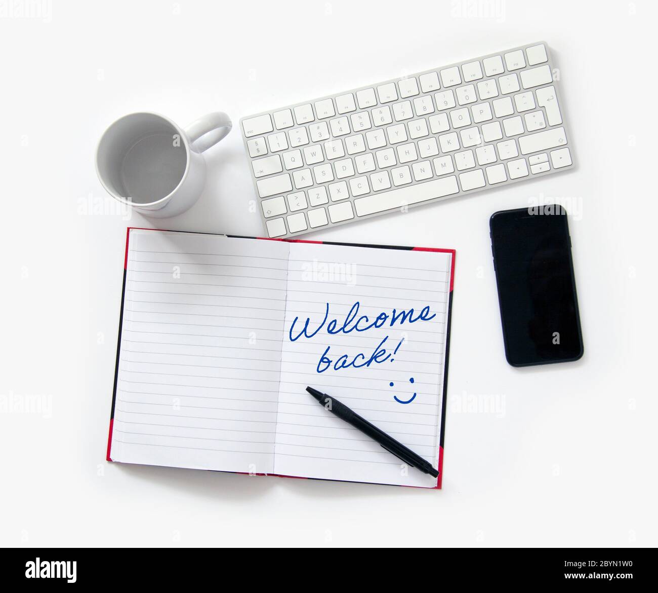 Welcome Back to Work Konzept. Linierte Notizblock Computer Tastatur Handy ein Bleistift und eine Kaffeetasse sind redy für im Büro wieder nach dem C beginnen Stockfoto