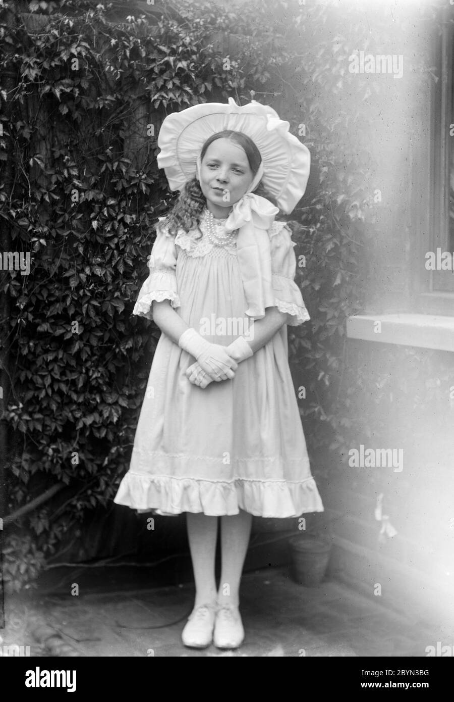 Ein altes englisches Schwarz-Weiß-Foto aus dem späten viktorianischen oder frühen Edwardianischen Zeitalter von einem jungen Mädchen, das Mode und Stil der Zeit zeigt. Stockfoto