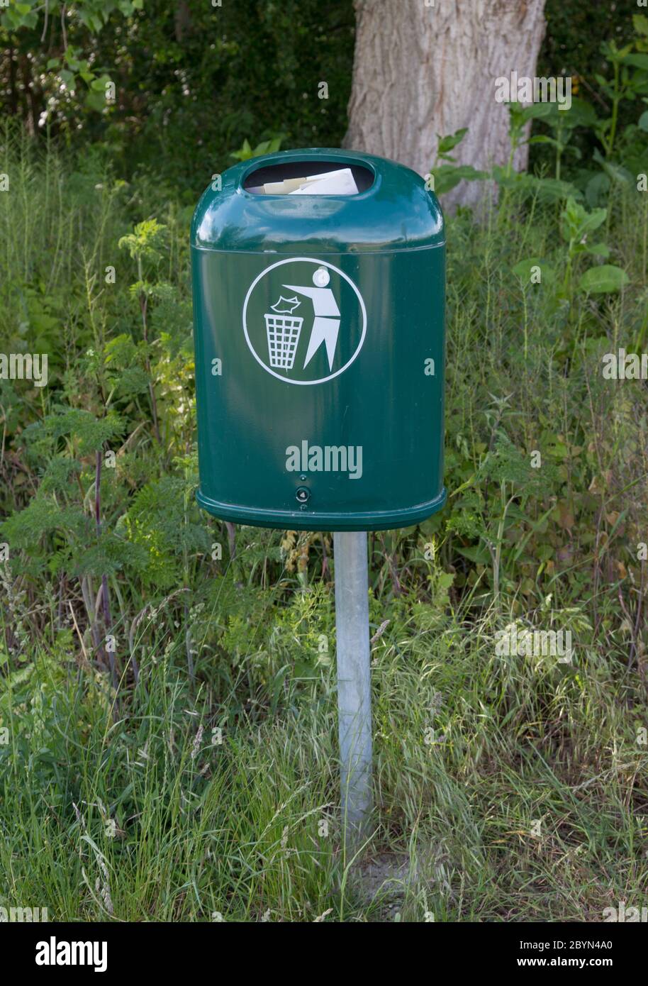 Gefüllter grüner Mülleimer in einer Landschaft Stockfoto