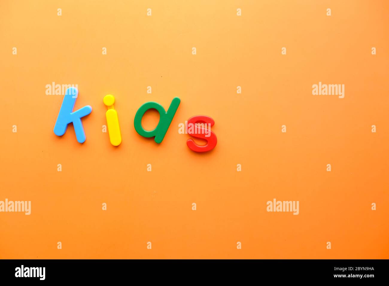 Bunte Plastikbuchstaben auf orangefarbenem Hintergrund, Draufsicht Stockfoto