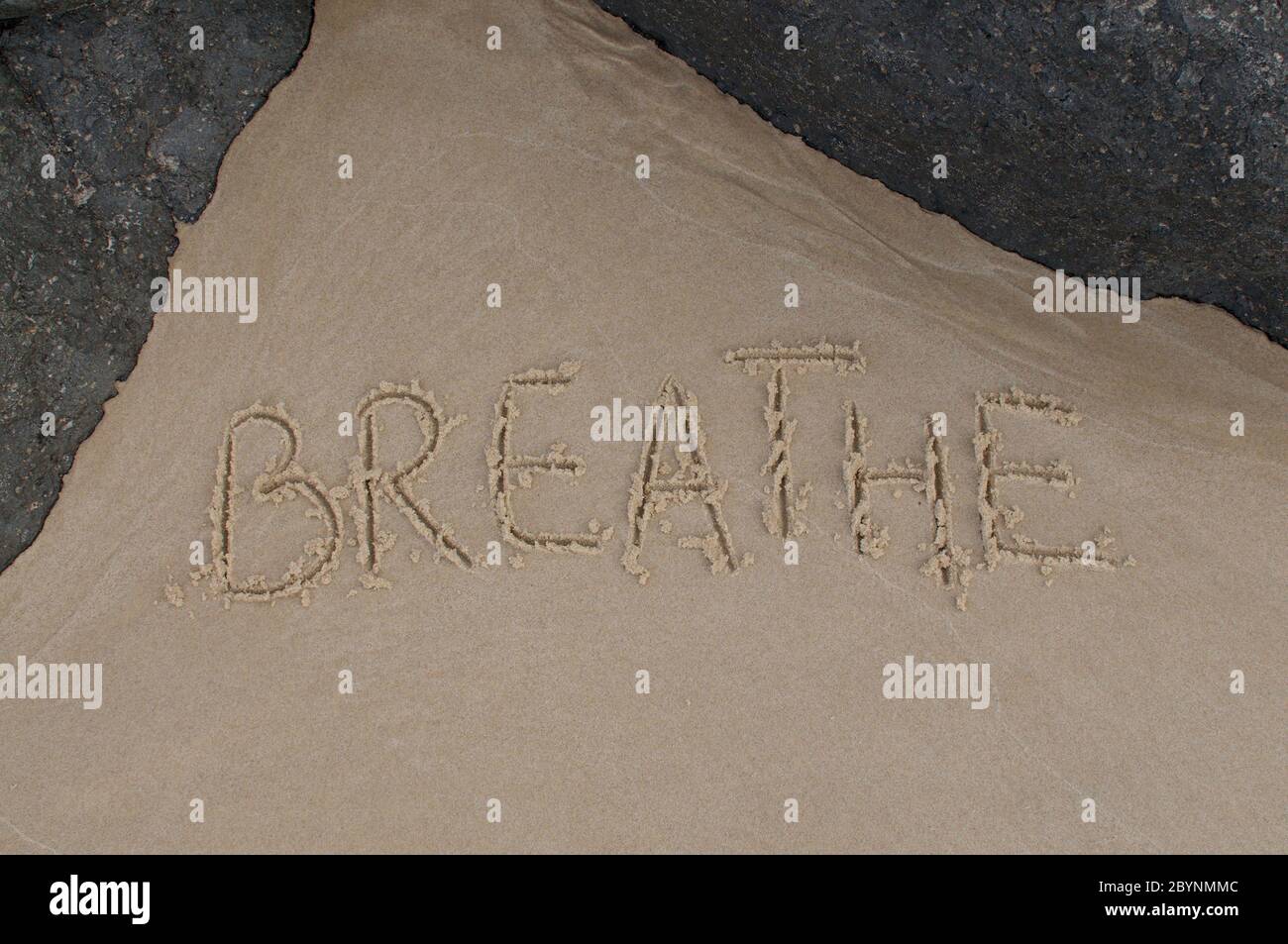 Atmen Sie Text Inschrift in der san gezeichnet und mit schwarzen Felsen eingerahmt Stockfoto