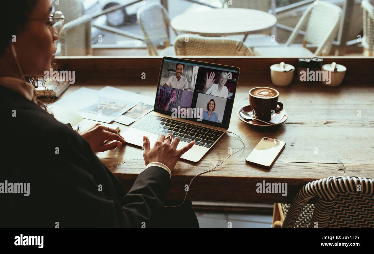 Geschäftsfrau, die einen Videoanruf in einem Café macht. Frau, die in einem Café sitzt und eine Videokonferenz mit ihrem Team führt. Stockfoto