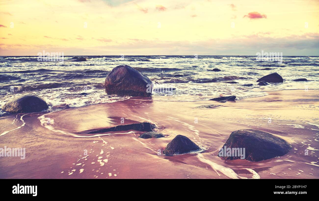 Landschaftlich schöner Strand mit Steinen bei Sonnenuntergang, Farbgebung angewendet. Stockfoto