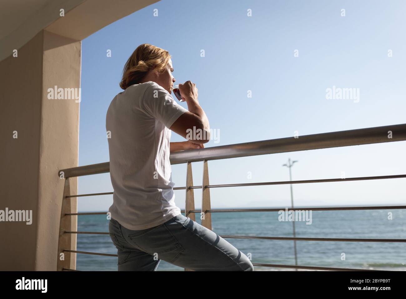 Kaukasischer Mann trinkt Kaffee auf einem Balkon Quarantäne-Sperre für Coronavirus Covid19 Pandemie Stockfoto