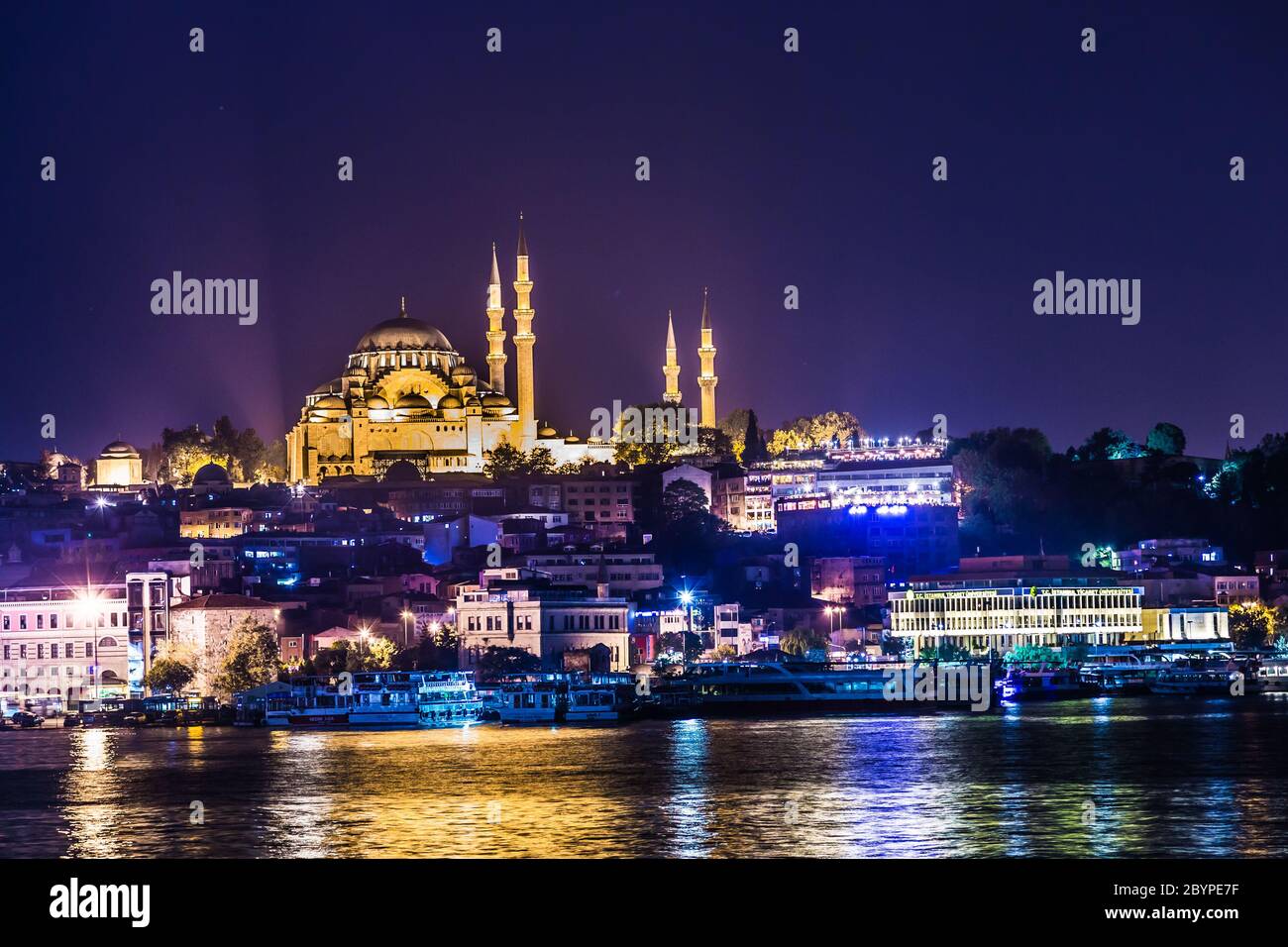 Nachtansicht auf die Restaurants am Ende der Galata Brücke, Sultanahmet, bei Sonnenuntergang mit der berühmten Suleymaniye Moschee in der Stockfoto