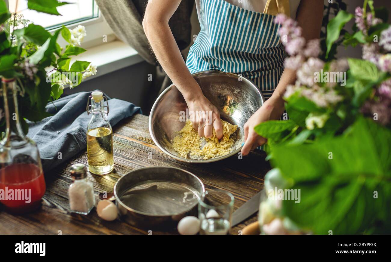 Eine Frau bereitet frischen Teig in gemütlicher Atmosphäre zu. Konzept der Zubereitung von leckeren Teiggerichten zu Hause. Stockfoto