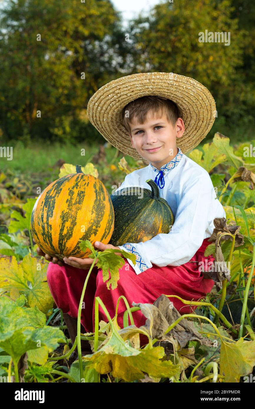 Lächelnder Junge mit großem gelben Kürbis in den Händen Stockfoto