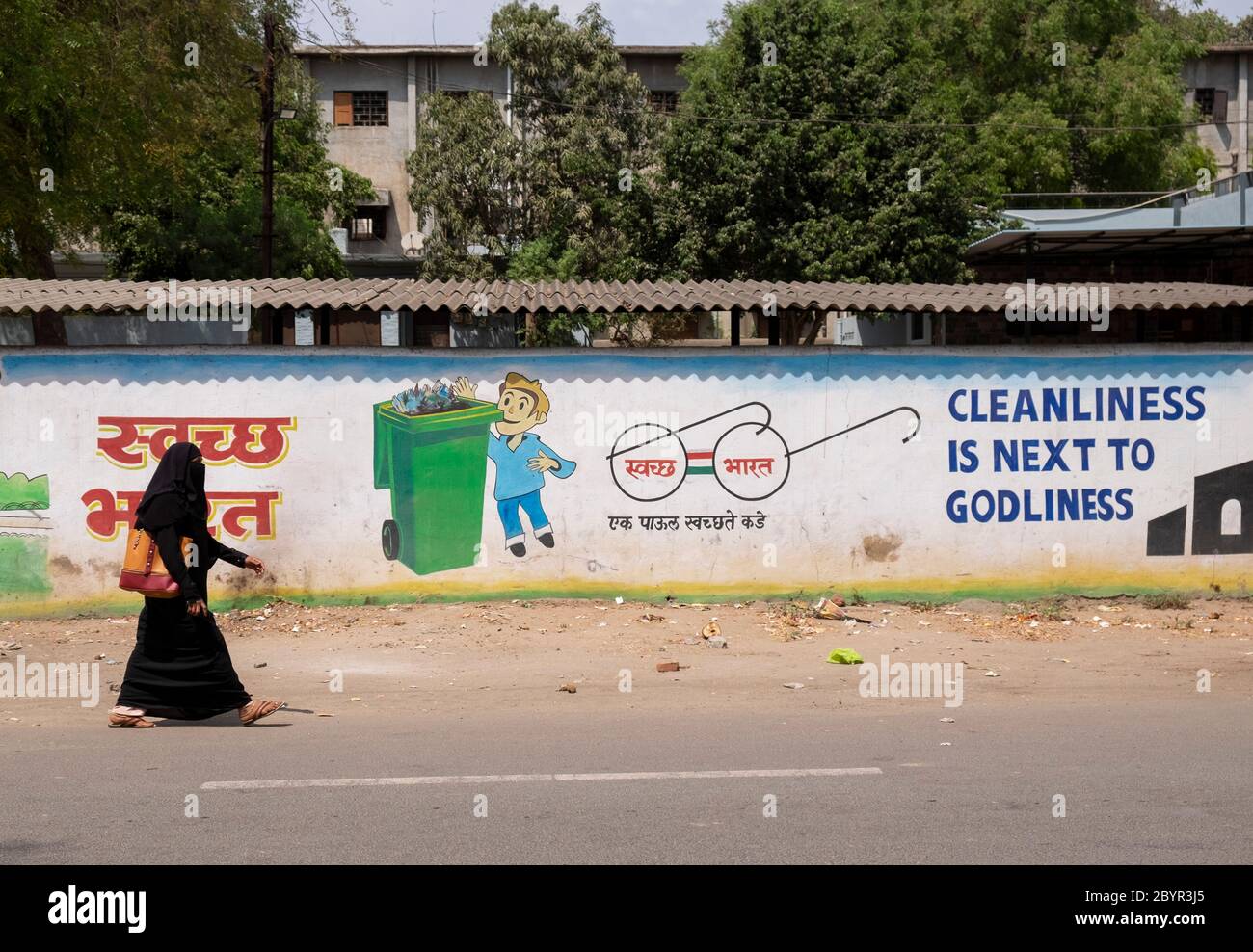 Lokale Frau, die an einer Mauer mit einem Slogan für ein sauberes Indien, Aurangabad, Maharashtra, Indien vorbeigeht. Stockfoto