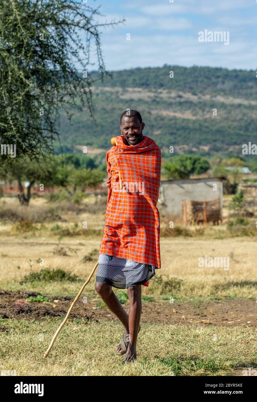 Masai Mann in traditioneller Kleidung steht in der Savanne. Tansania, Ostafrika, 12. August 2018. Stockfoto