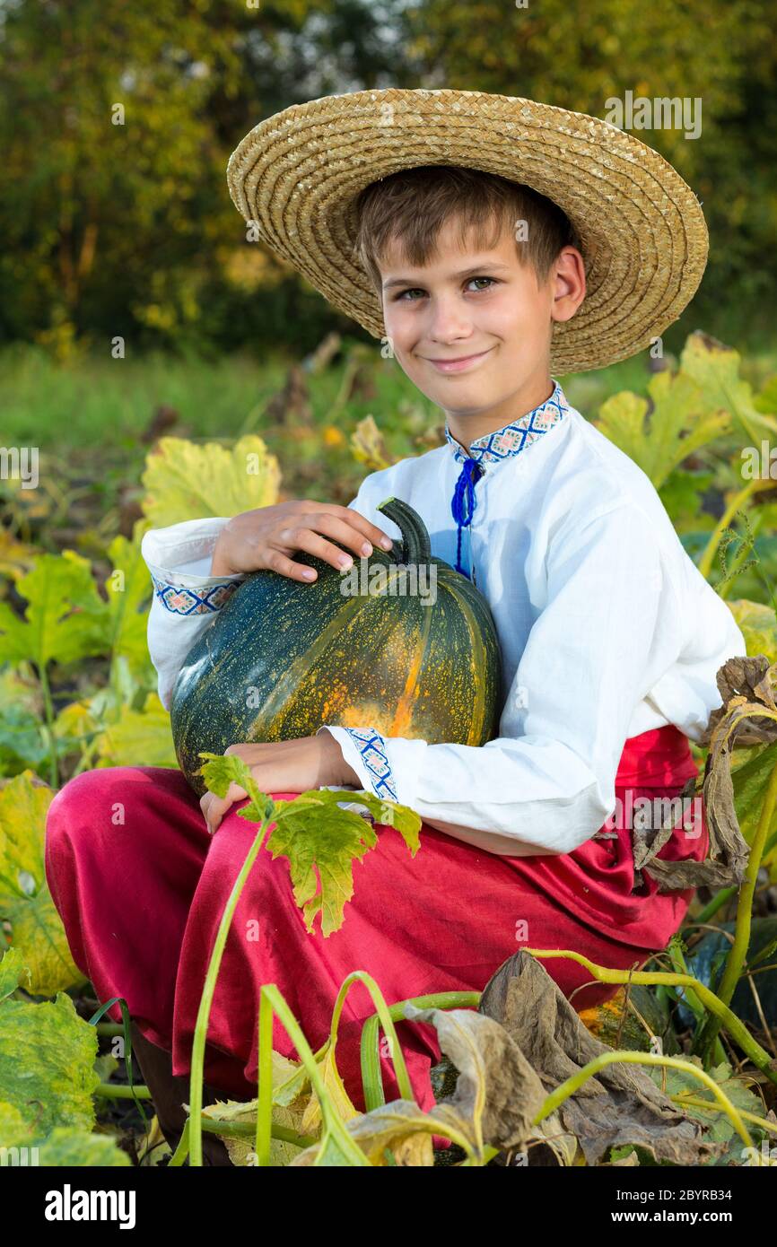 Lächelnder Junge mit großem gelben Kürbis in den Händen Stockfoto