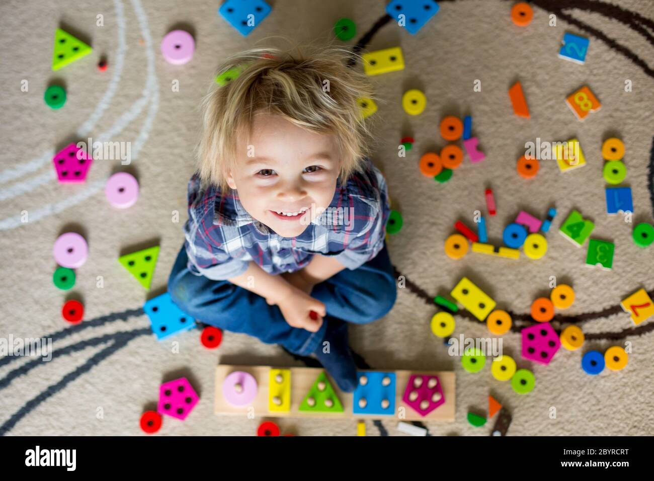 Kleine blonde Kleinkind Kind, Junge mit Holzspielzeug spielen Entwicklung und Lernaktivitäten Stockfoto