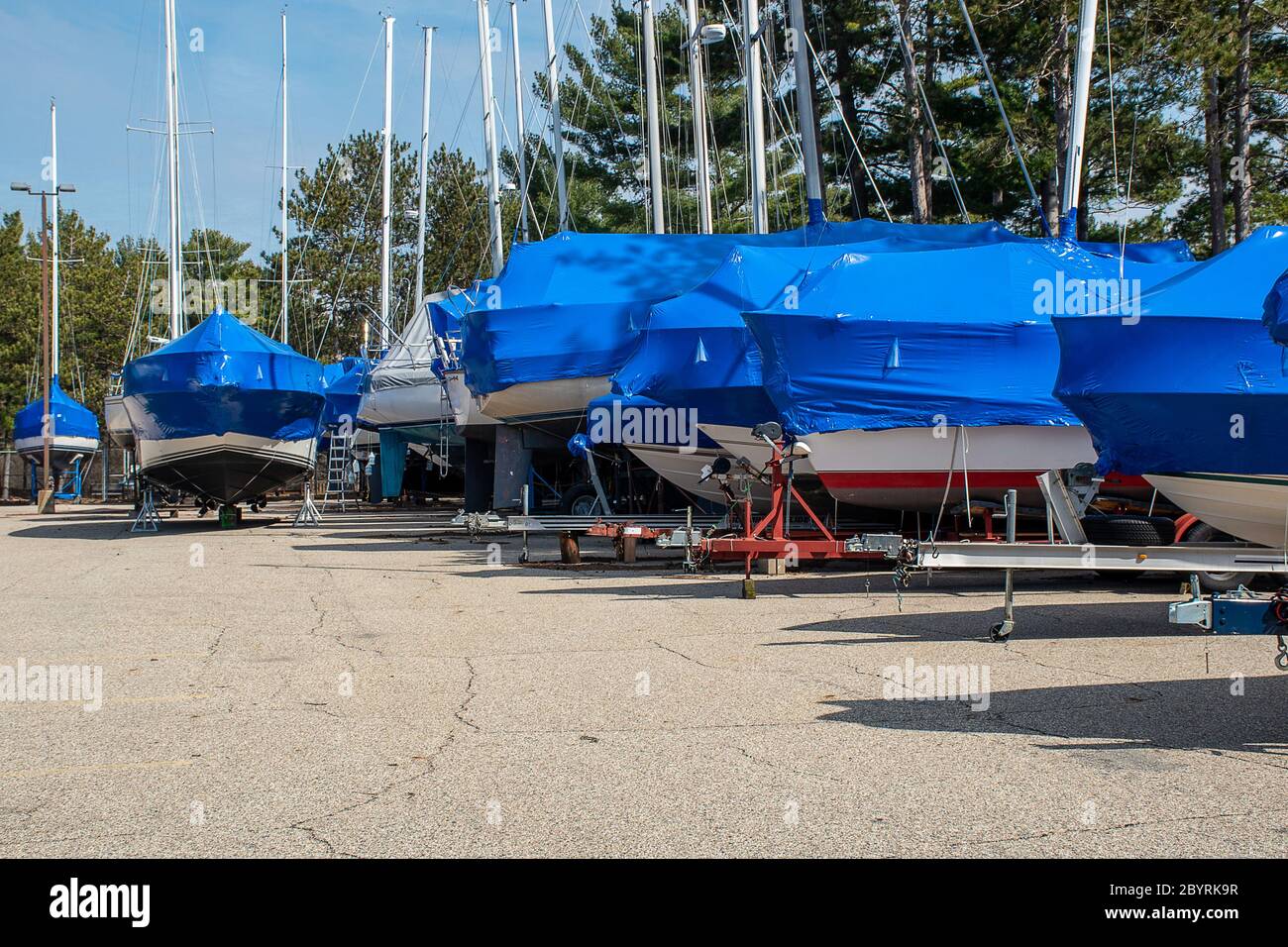 Reihe von Segelbooten mit blauen Schrumpffolie Abdeckungen im Outdoor-Lagerplatz Stockfoto
