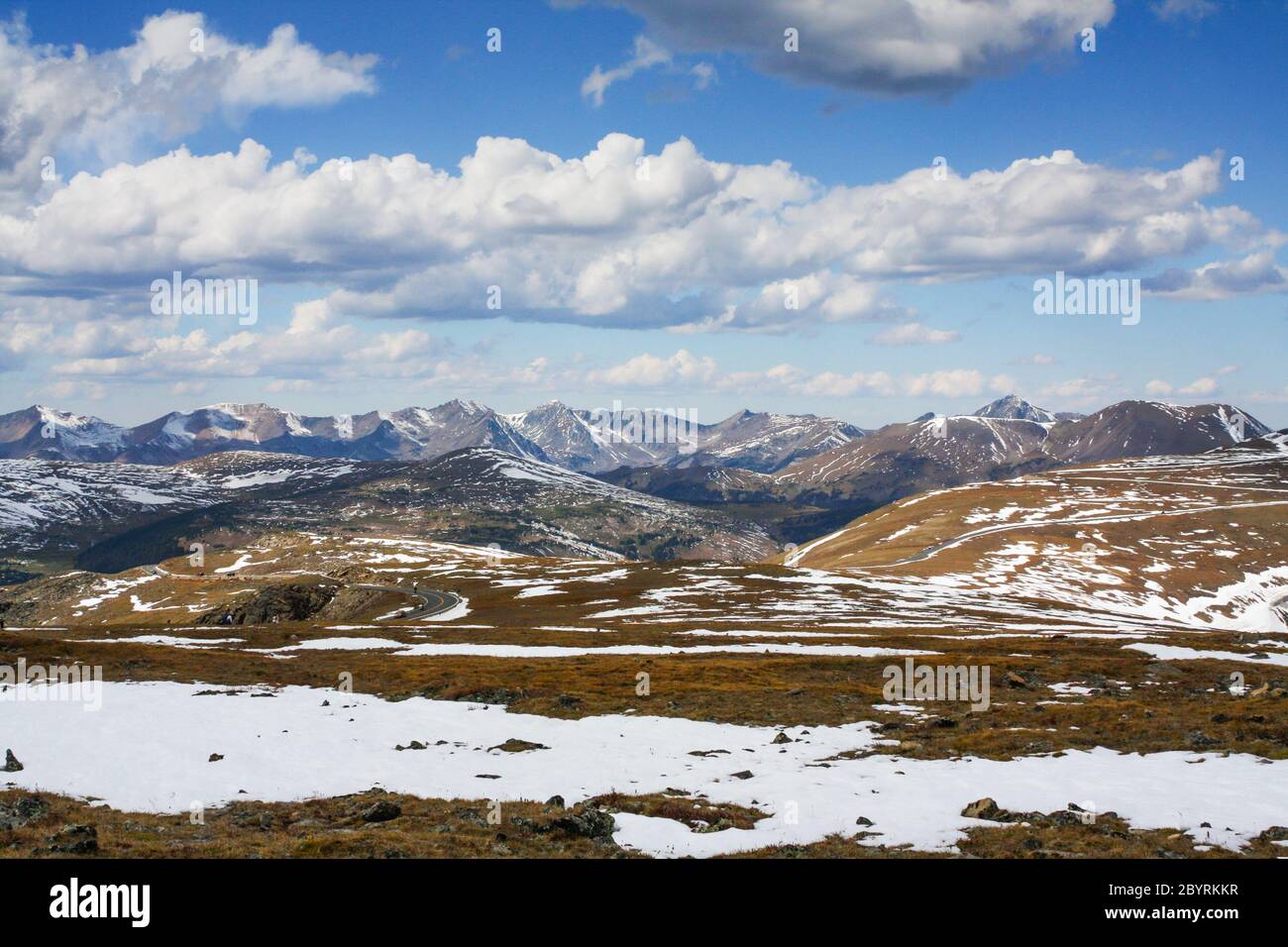 Blick auf Trail Ridge Road, die durch den Rocky Mountain National Park mit schneebedeckten Gipfeln der Berge "Never Summer" in der Ferne und Schnee führt Stockfoto