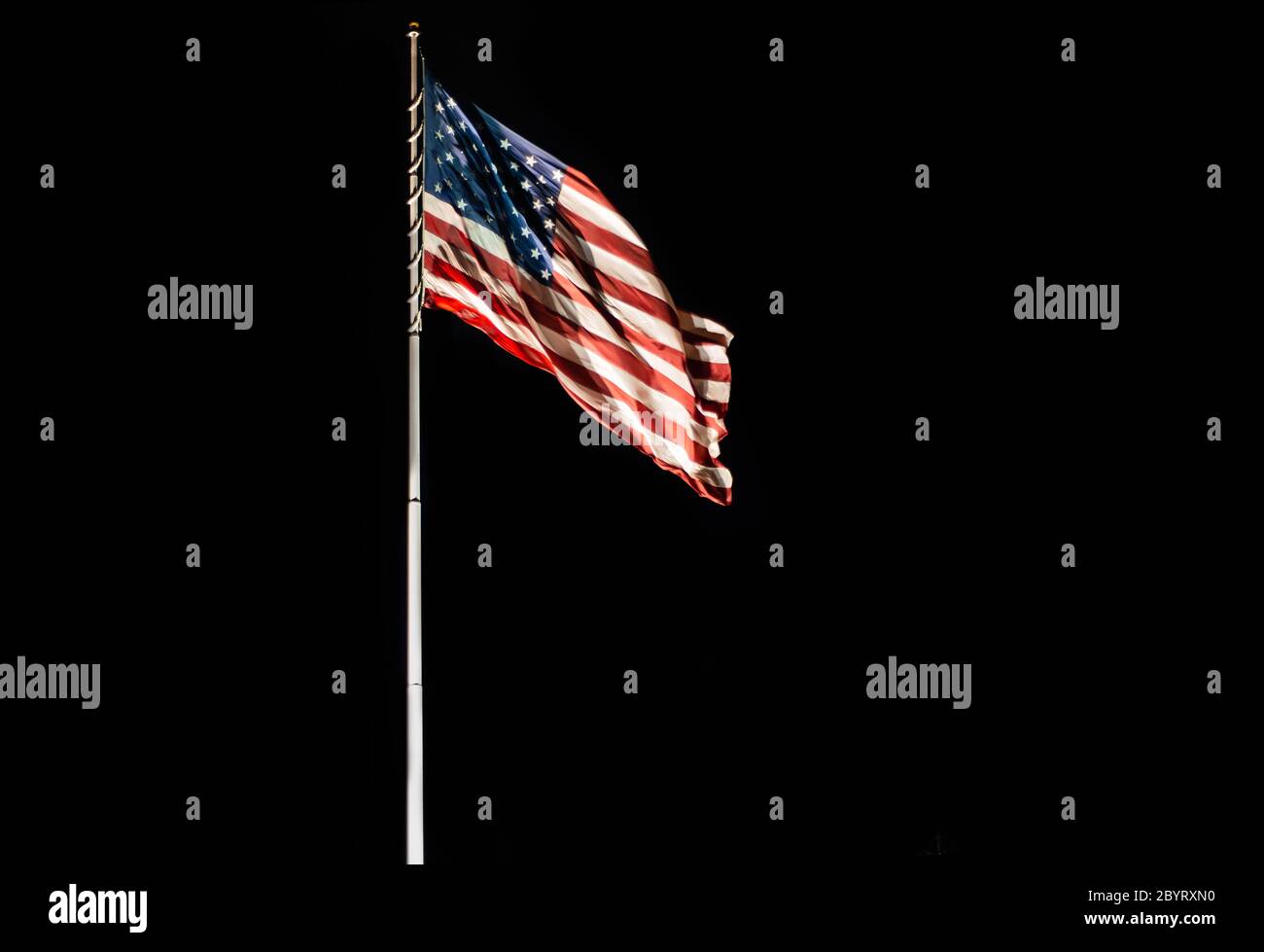 Stange mit winkender Old Glory amerikanische Flagge isoliert auf schwarzem, Copy Space Stockfoto