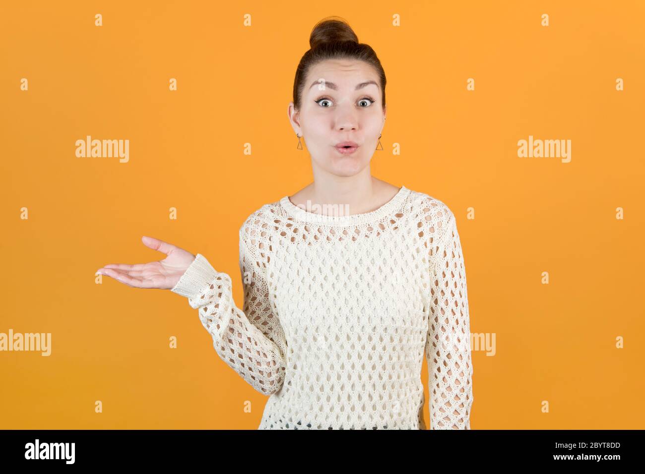 Mädchen hält seine Hand zur Seite, nimmt etwas und drückt Überraschung aus Stockfoto