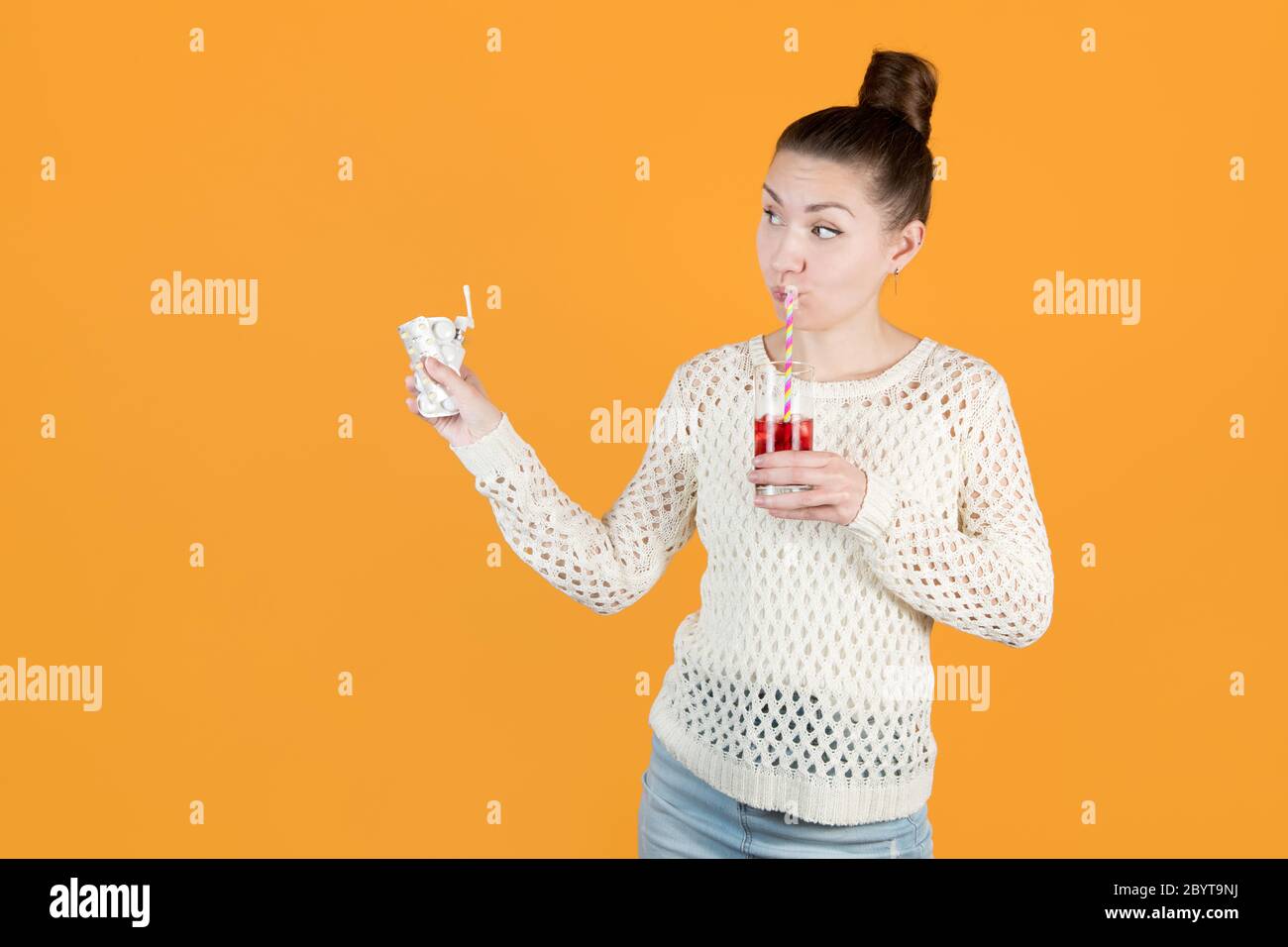 Mädchen hält Medikamente für Erkältungen aus, und sie trinkt Saft aus hellen Strohhalmen Stockfoto