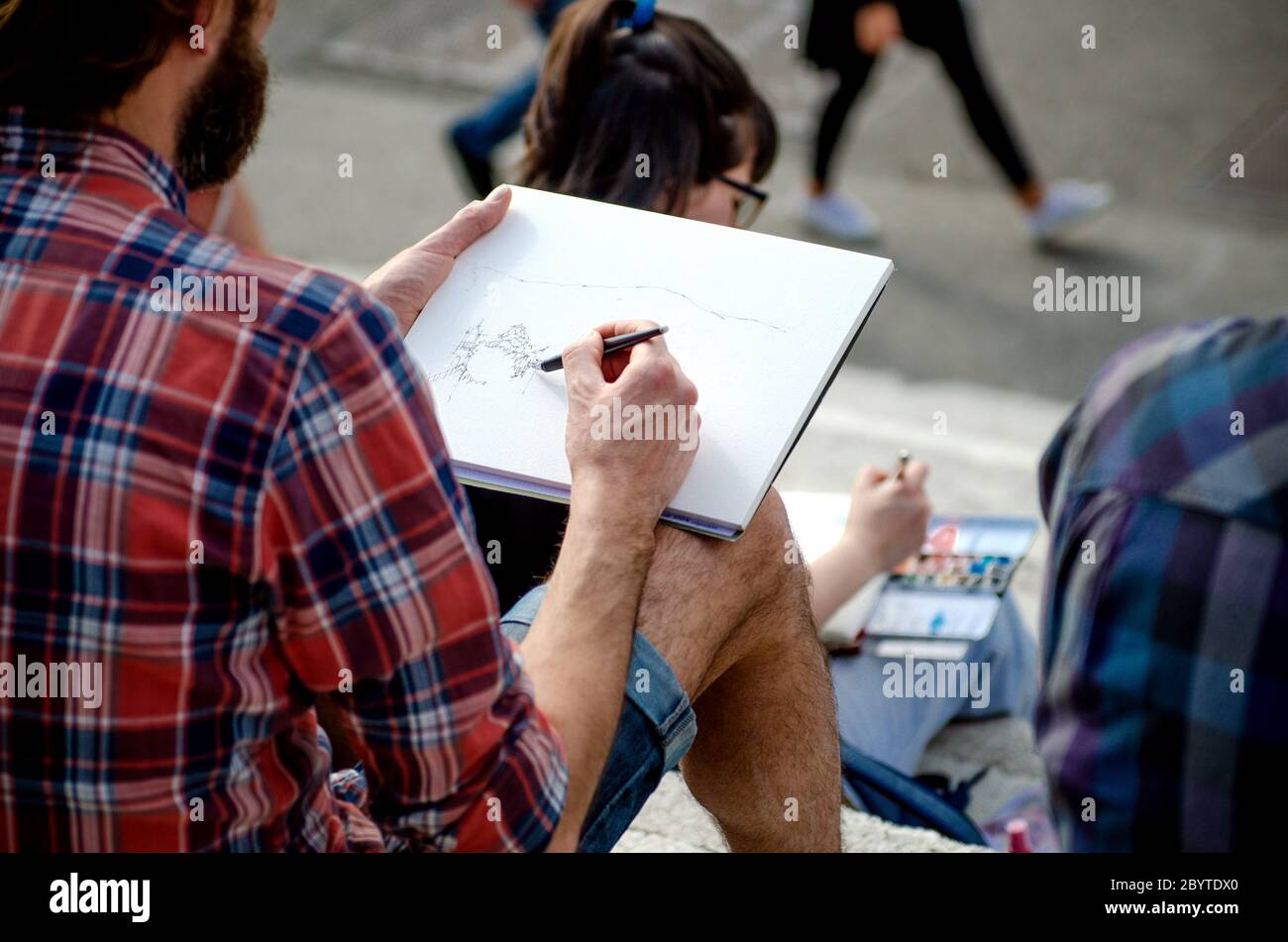 BARCELONA, SPANIEN - 18. MAI 2018. Junge bärtige Künstlerin malt auf einer Straße in Barcelona Stockfoto