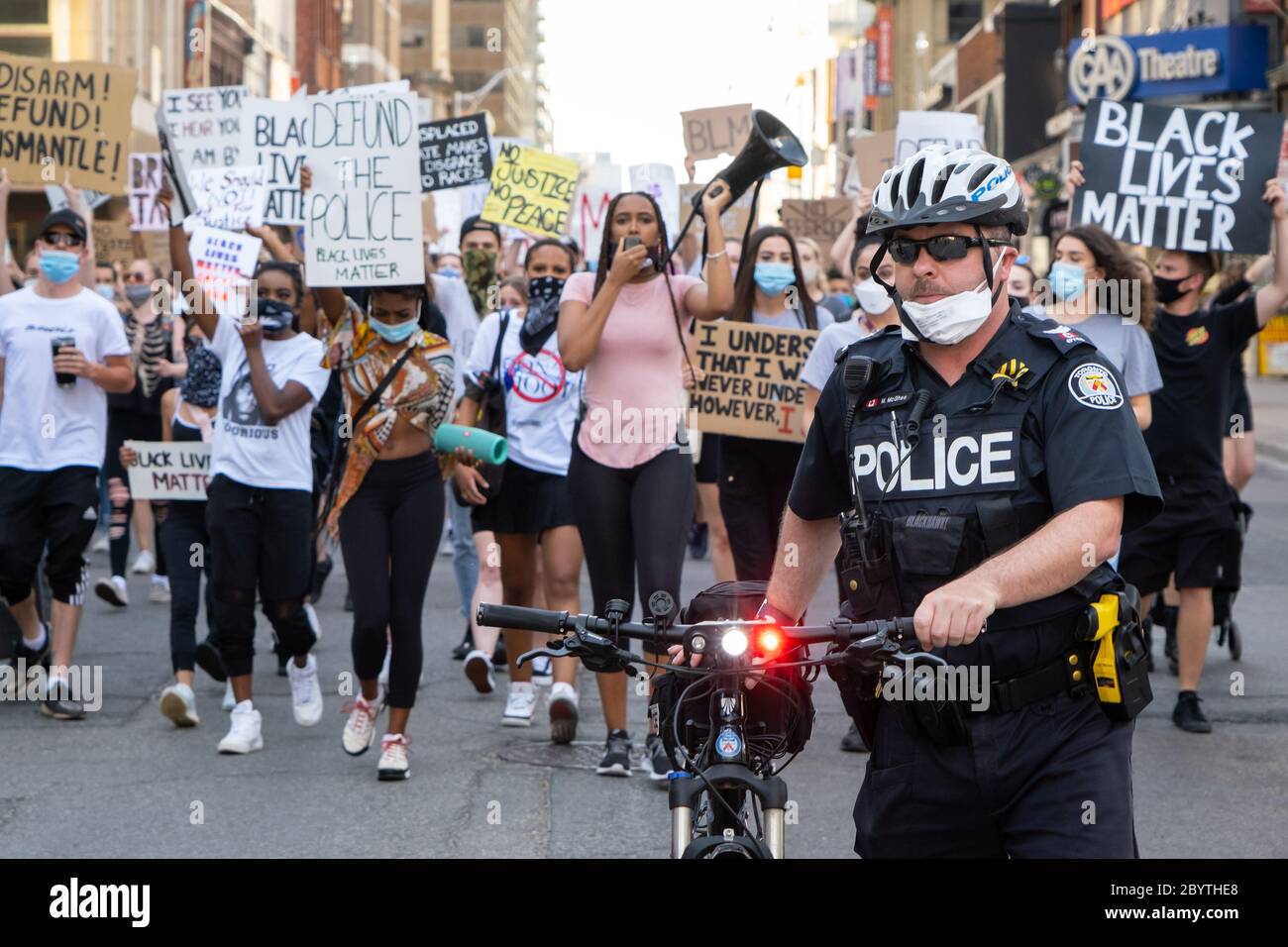 Ein Polizist geht vor einer Menge von Black Lives Matter Demonstranten, während sie die Strafverfolgung in Toronto, Ontario verurteilen. Stockfoto