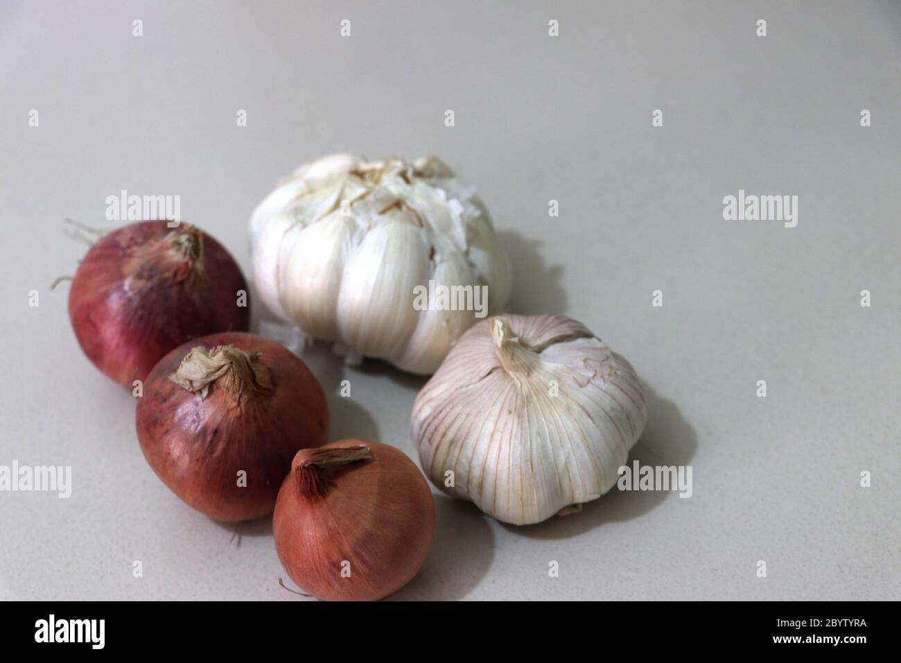 High Angle Ansicht von Zwiebeln und Knoblauch isoliert auf weißem Hintergrund ganze und Nelken Stockfoto
