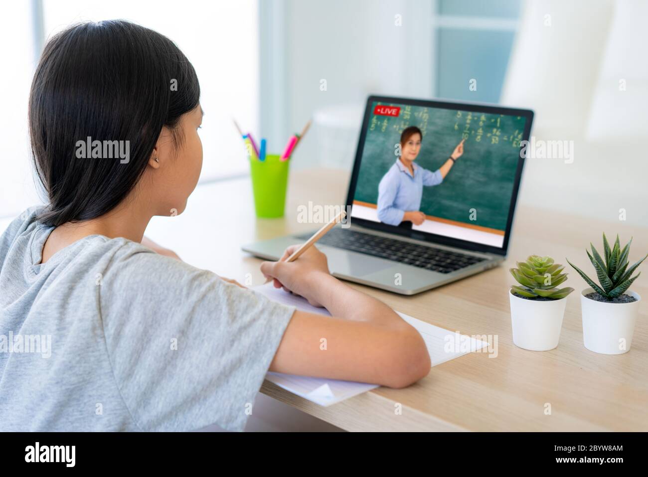 Asiatische Mädchen Student Videokonferenz E-Learning mit Lehrer auf Computer im Wohnzimmer zu Hause. Homeschooling und Fernunterricht, online, Bildung Stockfoto