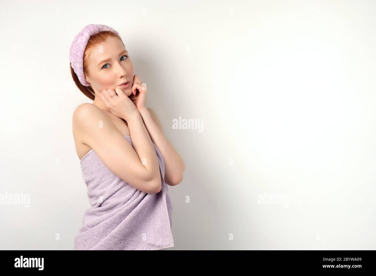 Nettes Rotschopf Mädchen steht in einer halben Umdrehung auf einem weißen Hintergrund Stockfoto