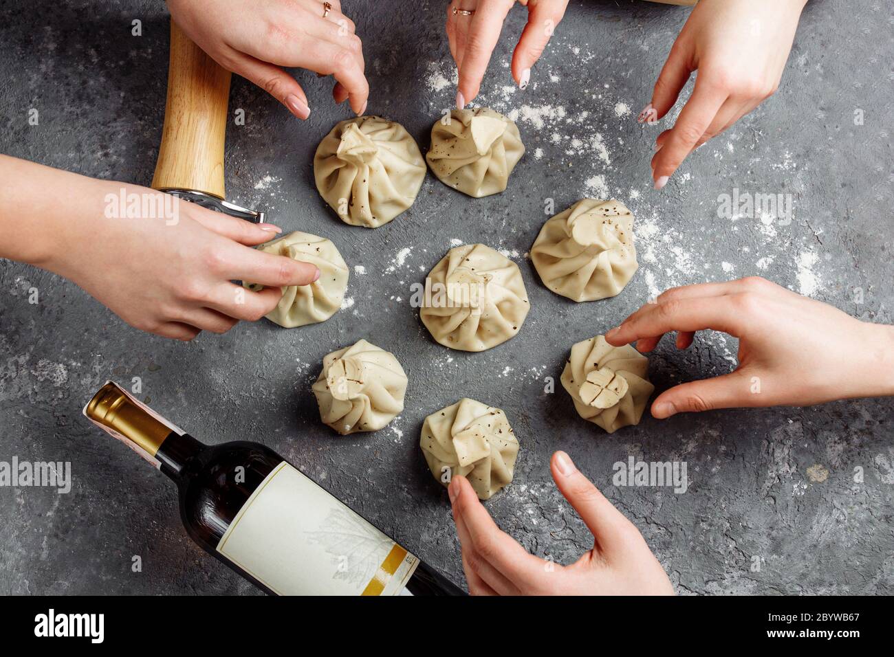 Khinkali, georgische Knödel, traditionelle georgische Küche. Hände von Menschen nehmen Khinkali von der Seite. Blauer Hintergrund, Kopierbereich. Stockfoto