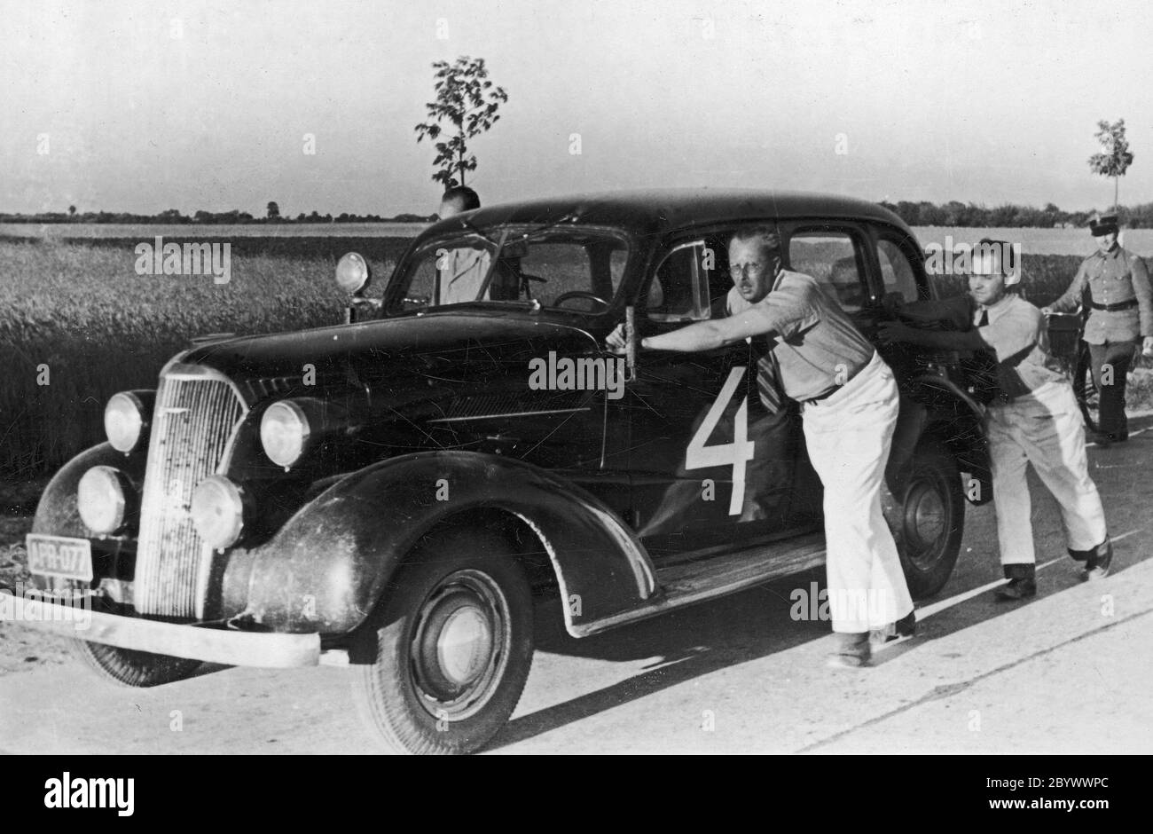 International Rally Automobile Club Poland, Grand Prix Poland 1937, neue Chevrolet Master Sedan mit seinem Fahrer Witold Rychter und Pilot Jerzy Wędrychowski. Das Fahrzeug ist nicht beschädigt. Sie schieben ihr Auto an den Startplatz in Łomianki, um eine Überhitzung zu vermeiden. 1937 Stockfoto