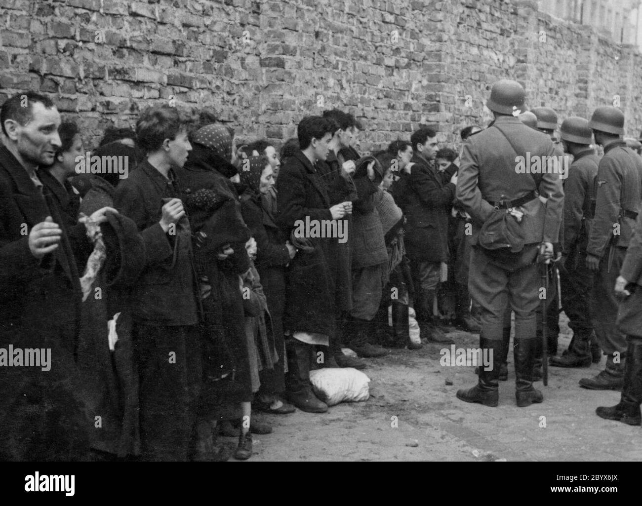 Warschauer Ghetto-Aufstand - Gefangene Juden werden nach Waffen gesucht und neben der Ghettomauer verhört, bevor sie auf den Umschlagplatz geschickt werden. 1943 Stockfoto