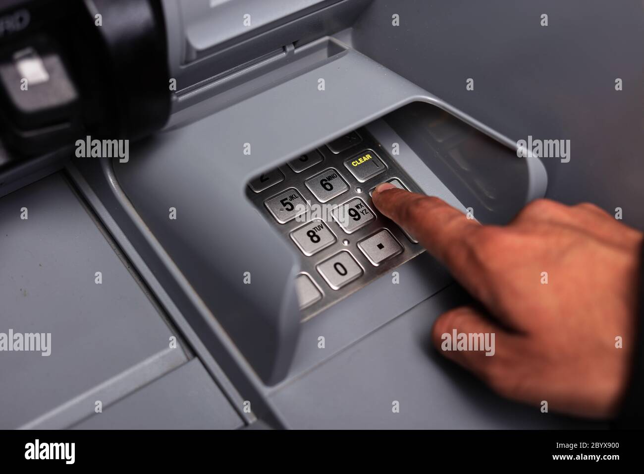 Nahaufnahme der männlichen Hand Eingabe der persönlichen Identifikationsnummer an einem Geldautomaten, um Bargeld abzuheben. Nahaufnahme. ATM-Transaktion. Weichzeichner. Tastatur. Stockfoto