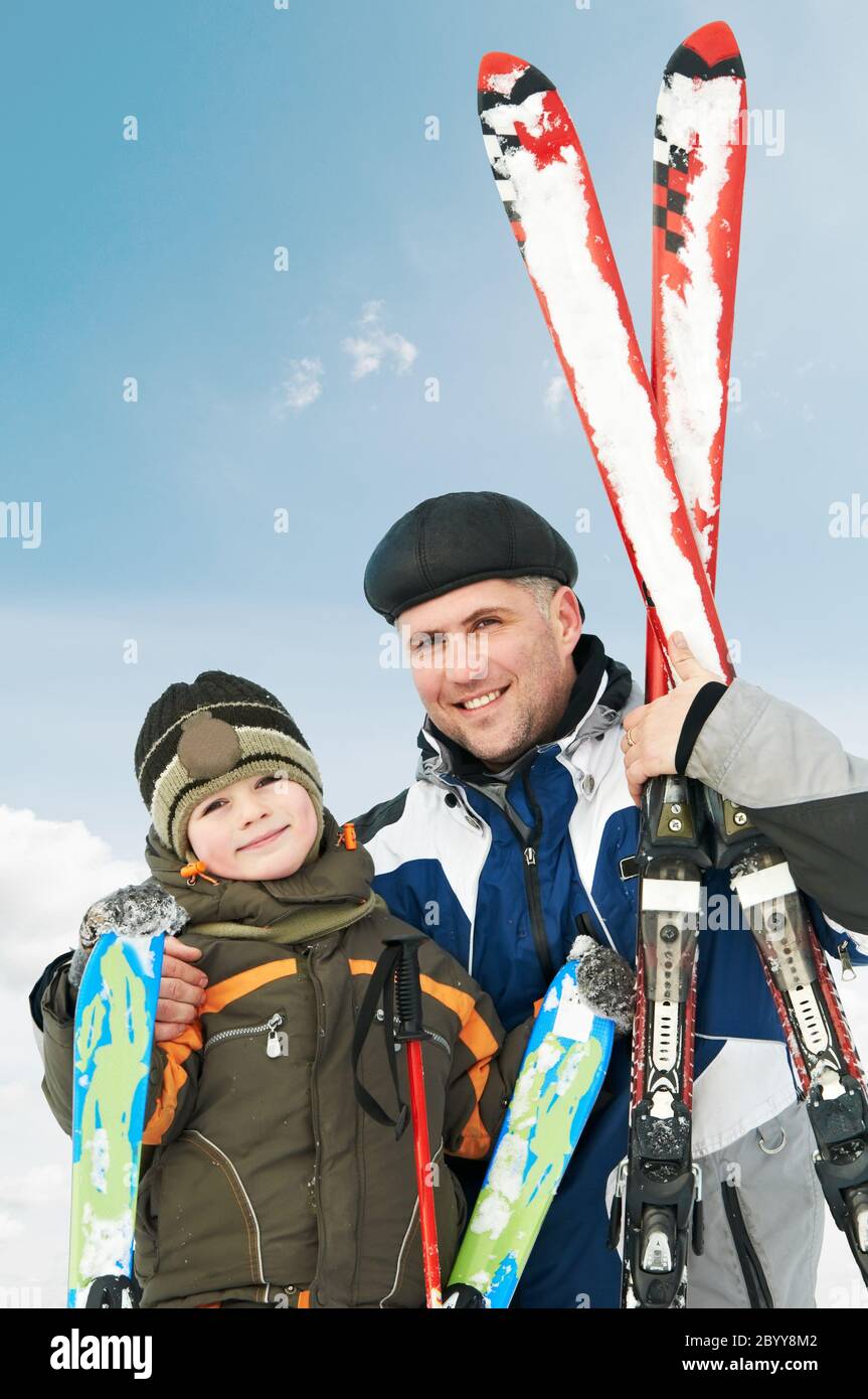 Lächelnder Sohn und Vater mit Skiern im Winter Stockfoto