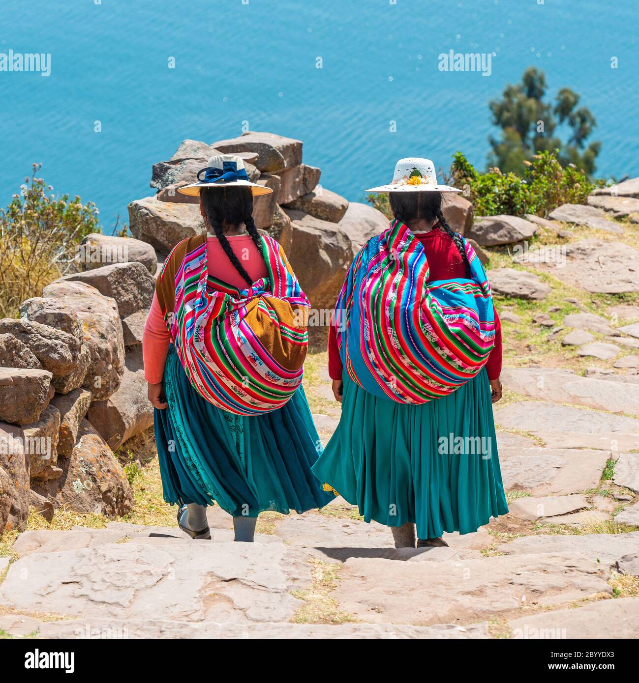 Indigene peruanische Quechua Frauen in traditioneller Kleidung, die Treppen auf der Taquile Insel, Titicaca See, Peru, hinuntergehen. Stockfoto