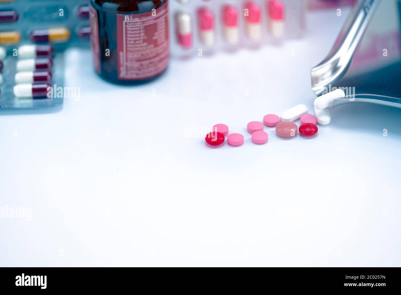 Rote, rosa und weiße Tabletten Pillen mit Drogentablett auf verschwommene Glas Drogenflasche und Blisterpackung. Geknackte Tabletten Pillen. Abgelaufene Medikamente. Schmerzmittel. Stockfoto