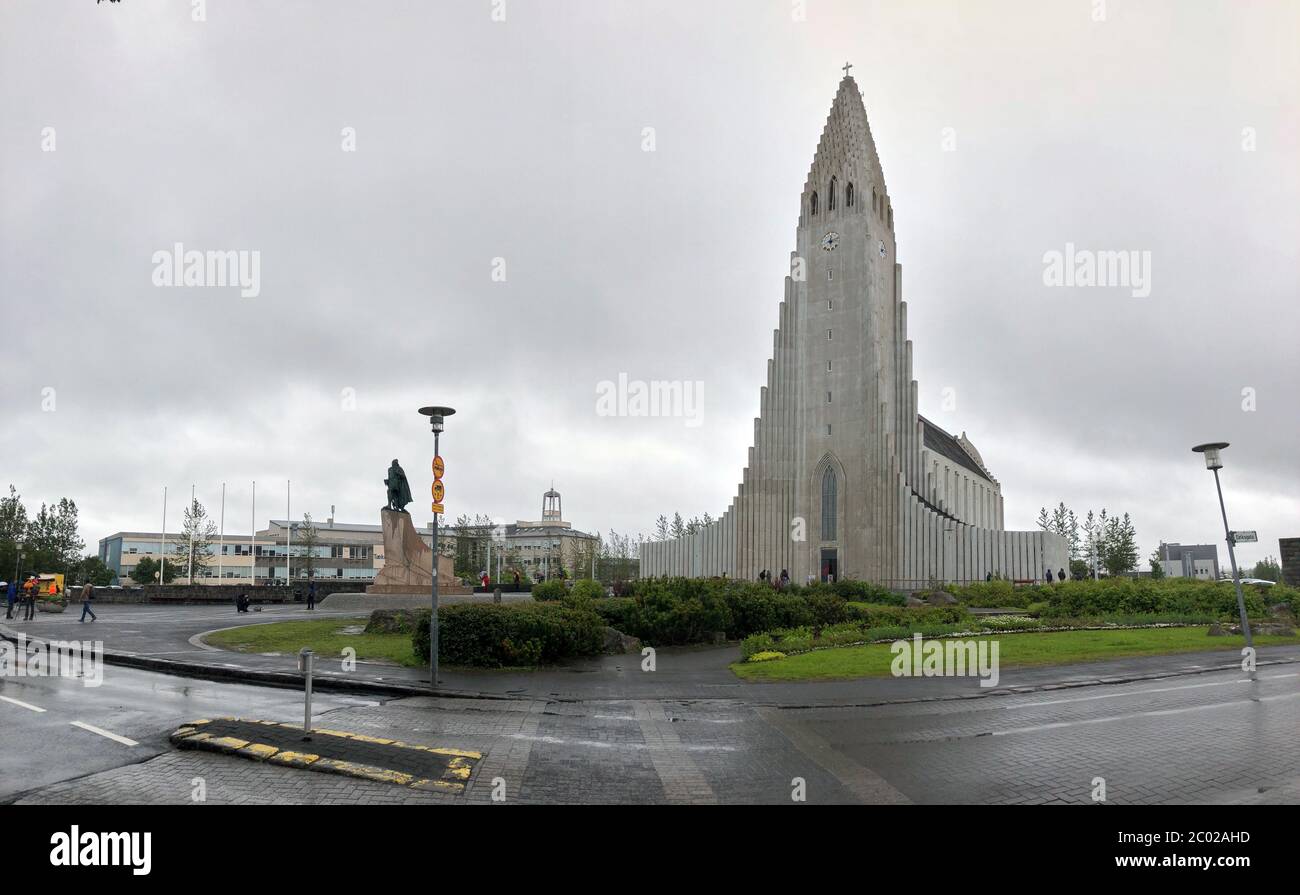 REYKJAVIK, ISLAND - 2. Juli 2018: Hallgrimskirkja, eine lutherische Pfarrkirche mit Leif Erikson Statur und Menschen am bewölkten Himmel. Kathedrale Gebäude wi Stockfoto