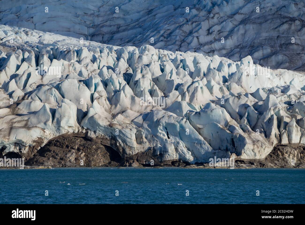 Beeindruckende Gletscherfront mit einem Felsen darunter. Fjord auf Spitzbergen in der Nähe des Nordpols. Stockfoto