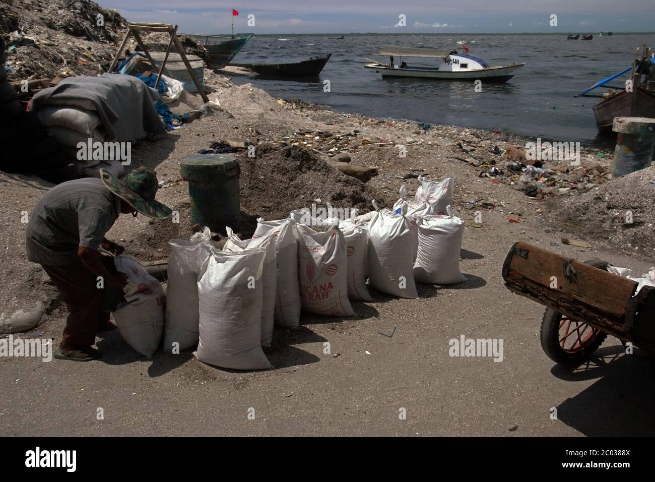 Man verpackt Sand und Material für die Rückgewinnung von Land und Küstenschutz, die von einer Deponie in Cilincing Fischerdorf, Nord Jakarta, Indonesien, stammen. Archivfoto. Stockfoto