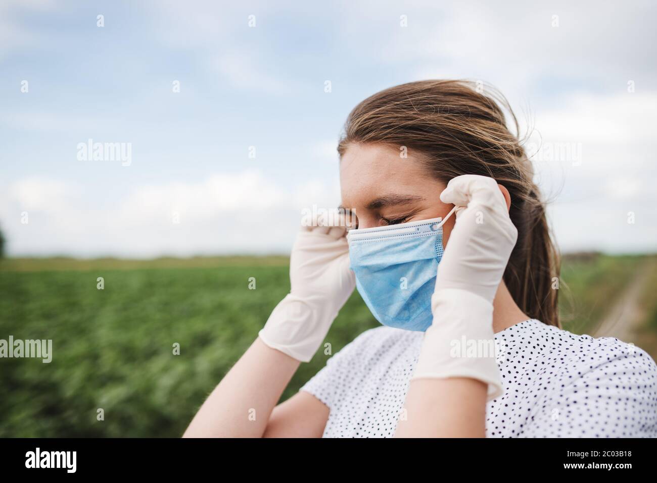 Die junge Frau trägt eine Virusschutzmaske und trägt sterile OP-Handschuhe an ihren Händen Stockfoto
