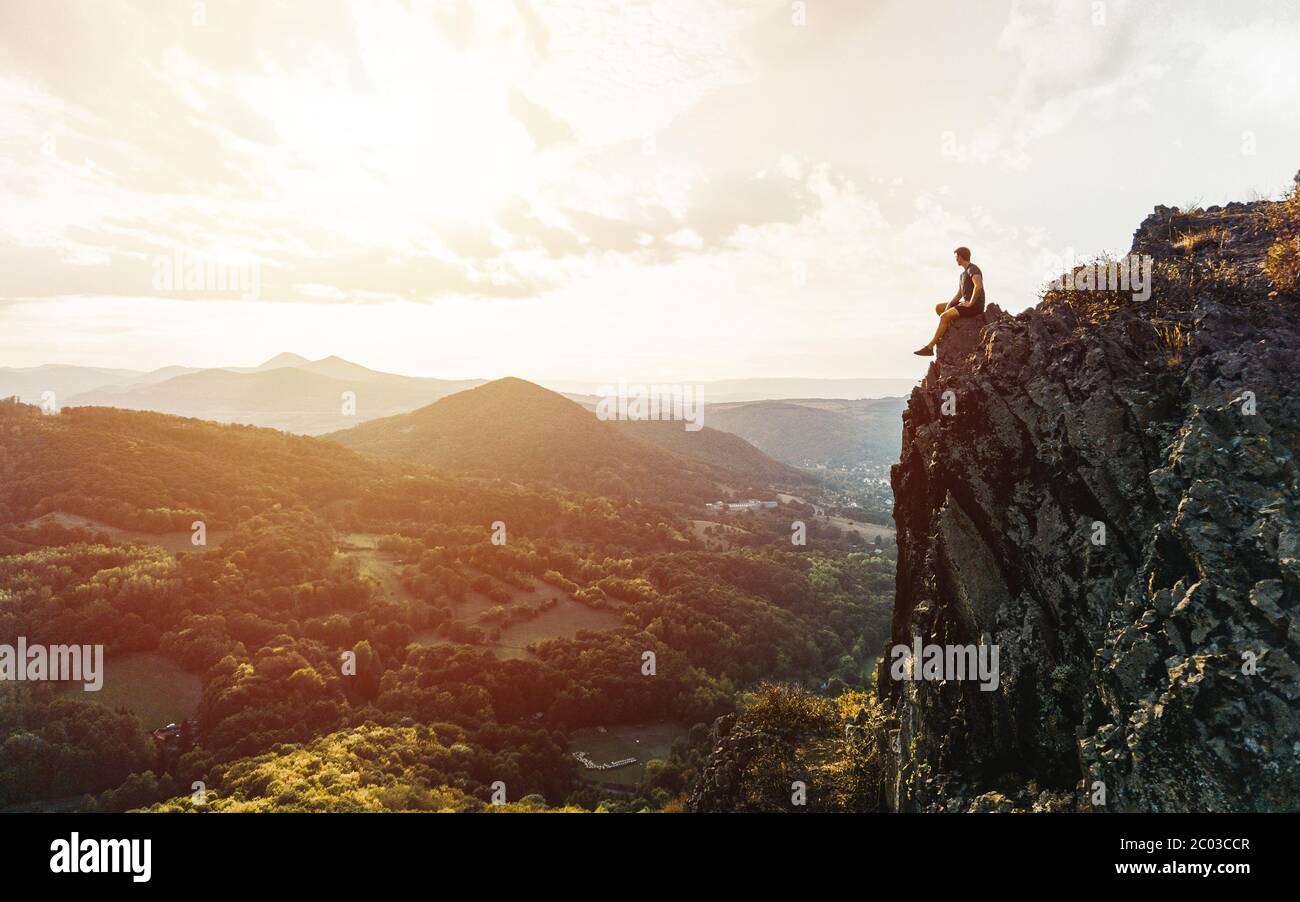 Reisen Mann Touristen allein auf den Rand der Klippen Berge und Blick auf das Tal. Silhouette der Person auf dem hohen Felsen bei Sonnenuntergang. Wanderabenteuer Stockfoto