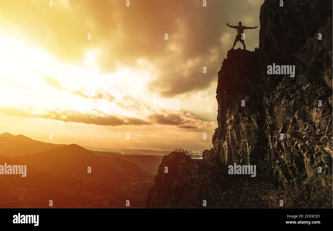 Reisen Mann Touristen allein auf den Rand der Klippen Berge und Blick auf das Tal. Silhouette der Person auf dem hohen Felsen bei Sonnenuntergang. Wanderabenteuer Stockfoto