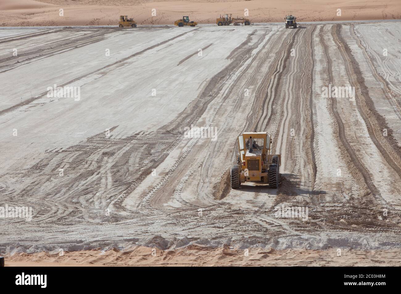 Schwere Ausrüstung, die Gips ausstreut, um eine Grundlage für eine Ölanlage in der Sahara zu bilden. Stockfoto