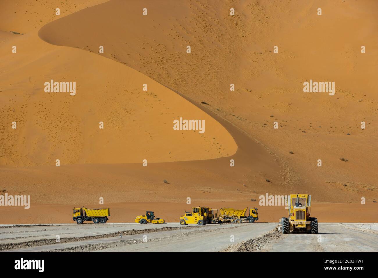 Schwere Ausrüstung, die Gips ausstreut, um eine Grundlage für eine Ölanlage in der Sahara zu bilden. Stockfoto